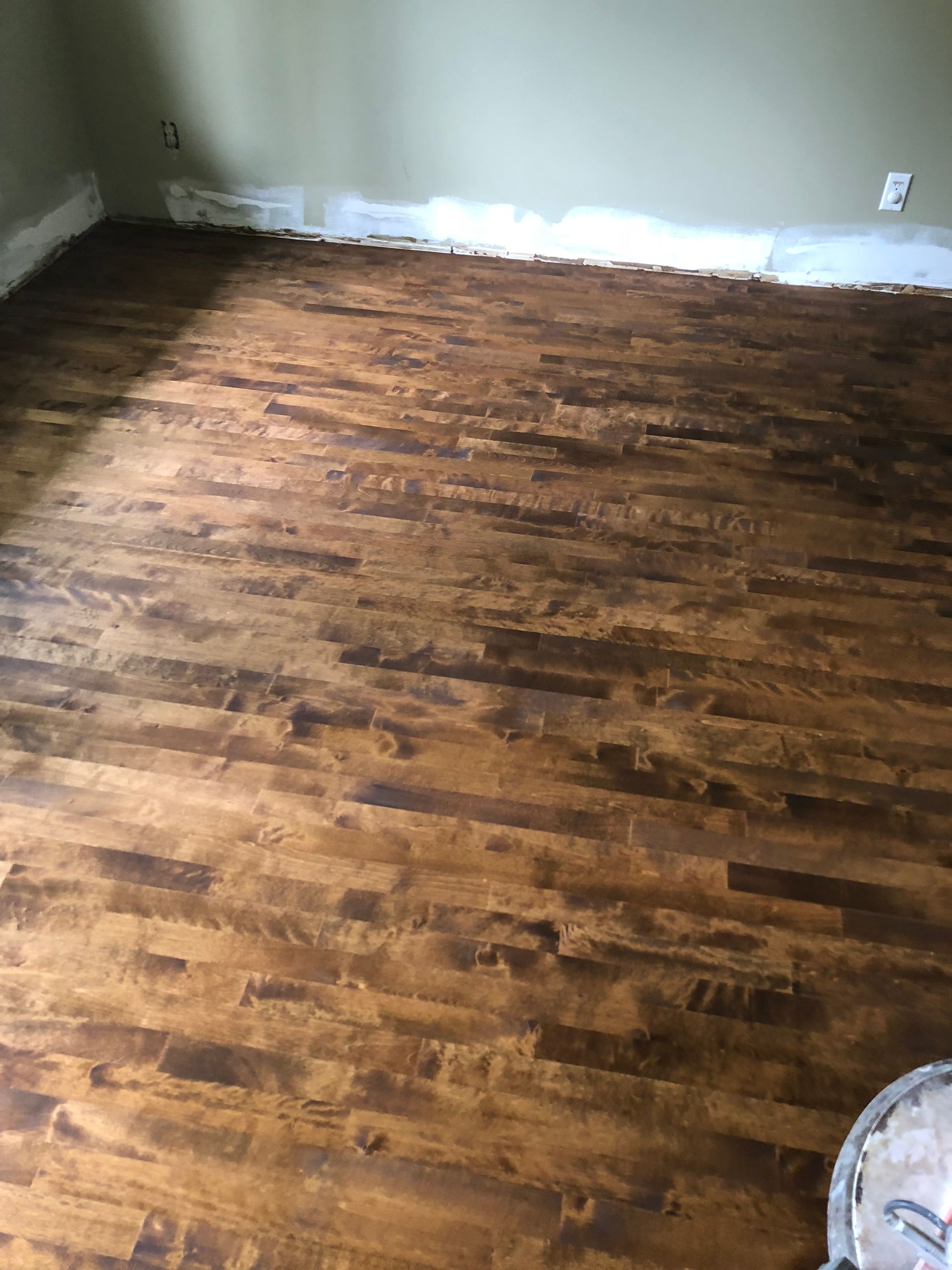 Une pièce avec du parquet et un mur blanc.