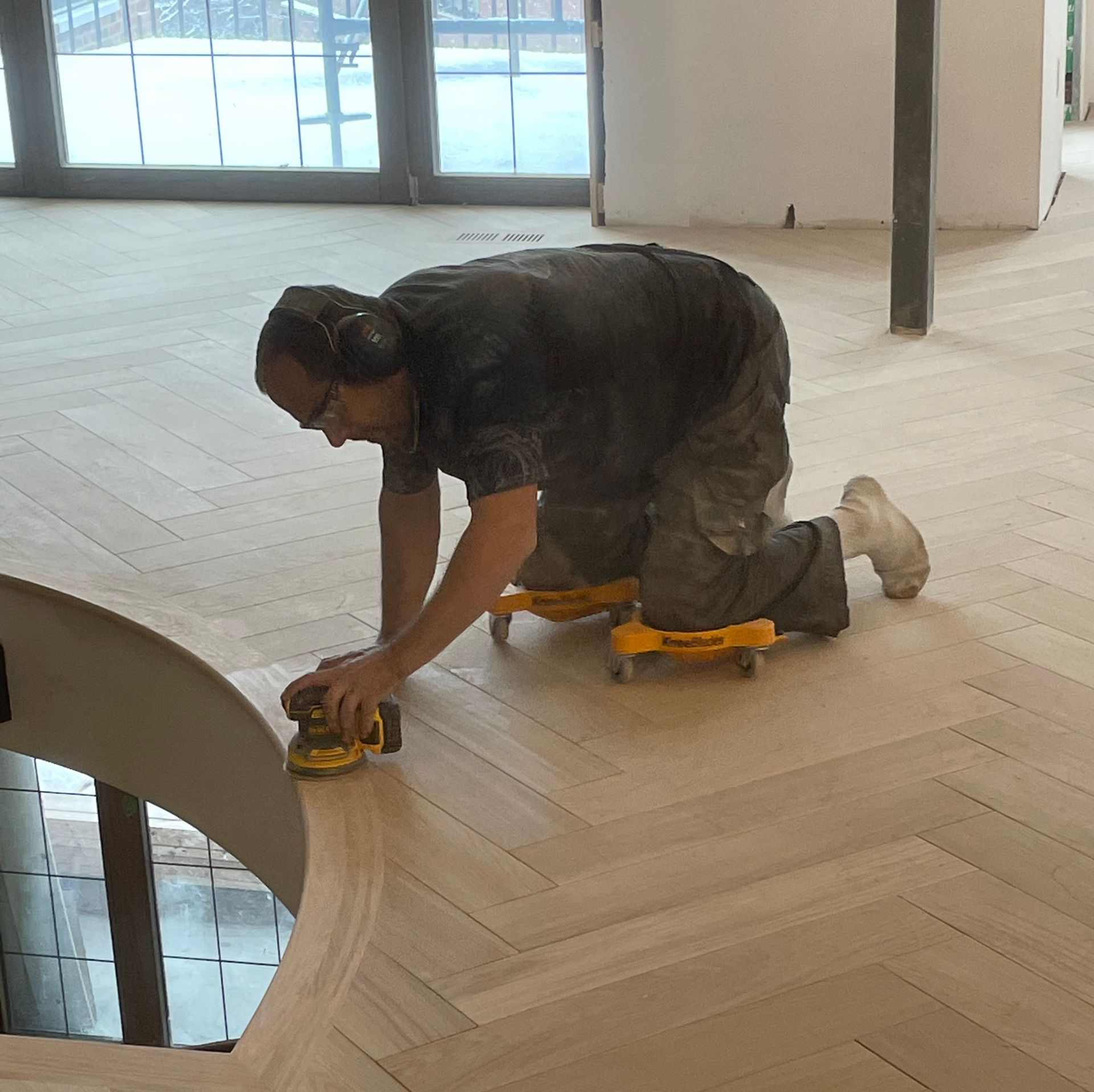 Un homme ponce un plancher en bois avec une ponceuse
