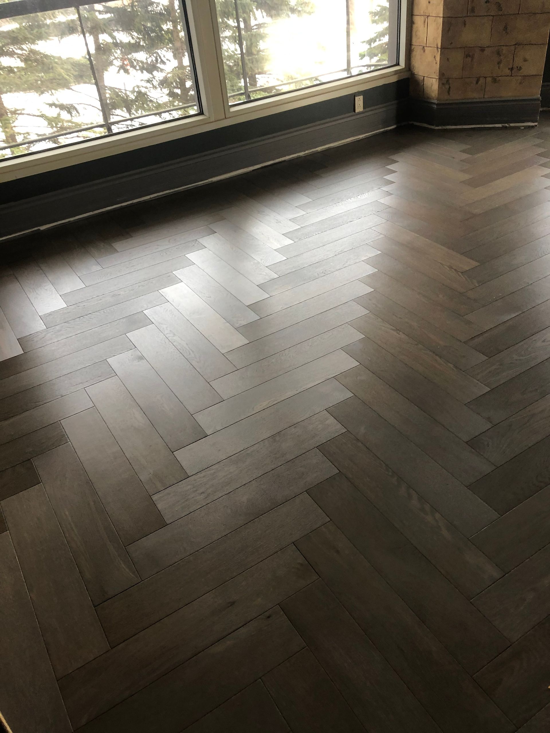 Une pièce avec un parquet à bâtons rompus et une grande fenêtre