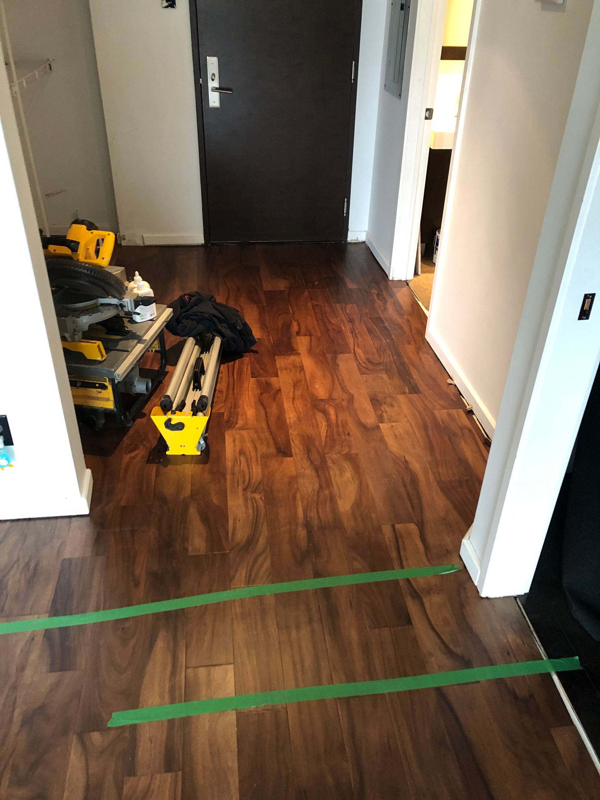 Un couloir avec parquet et ruban vert au sol.