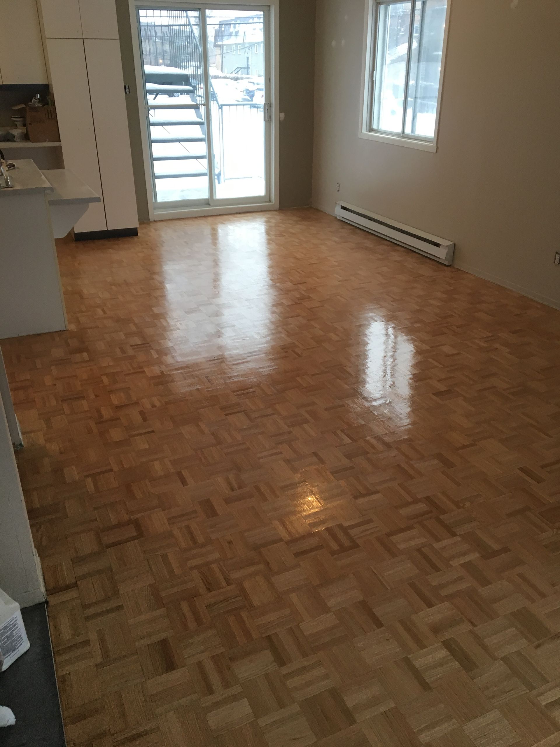 Un séjour avec parquet au sol et porte coulissante vitrée.