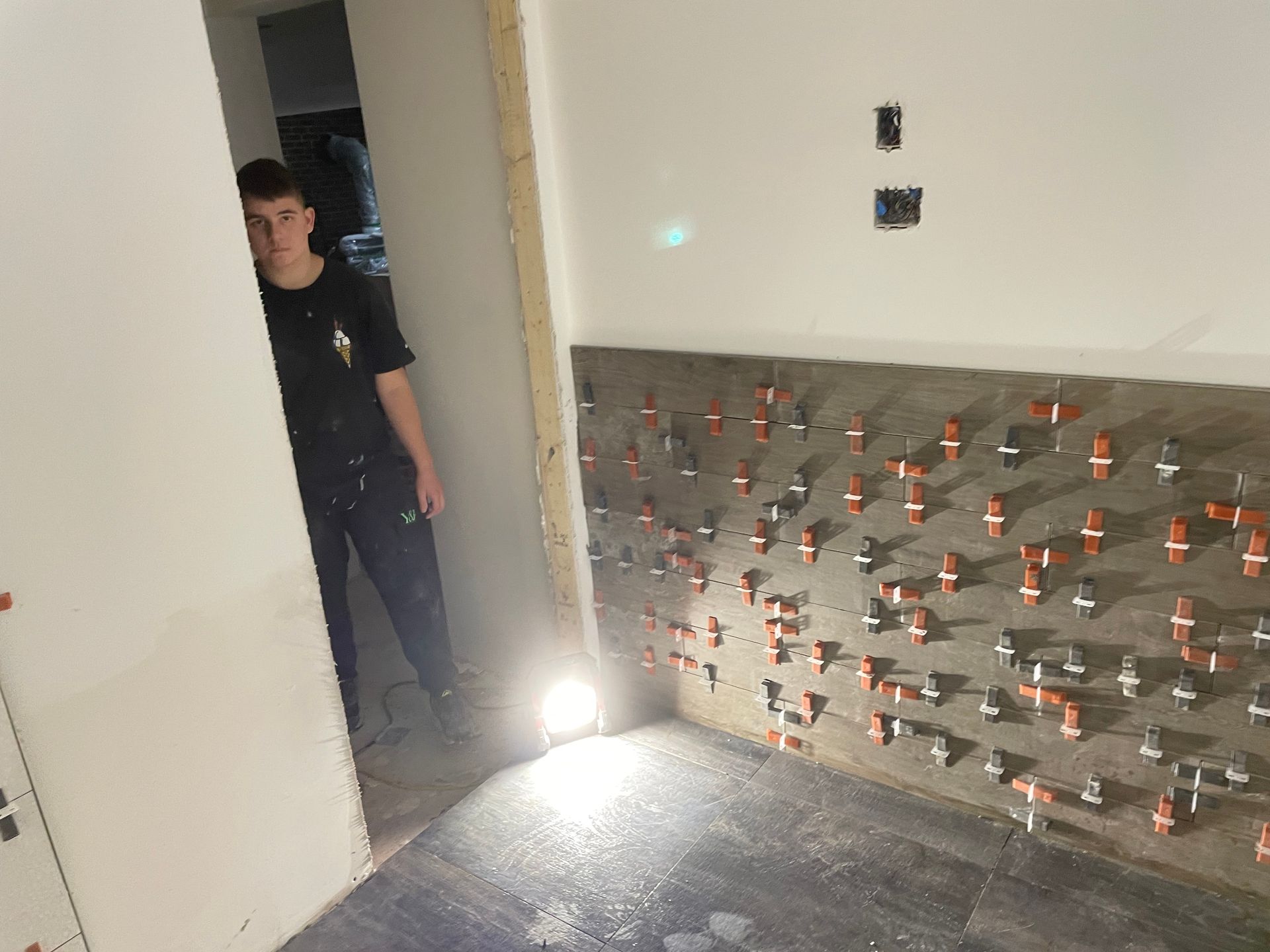 Un homme se tient dans une pièce avec beaucoup de carrelage aux murs.