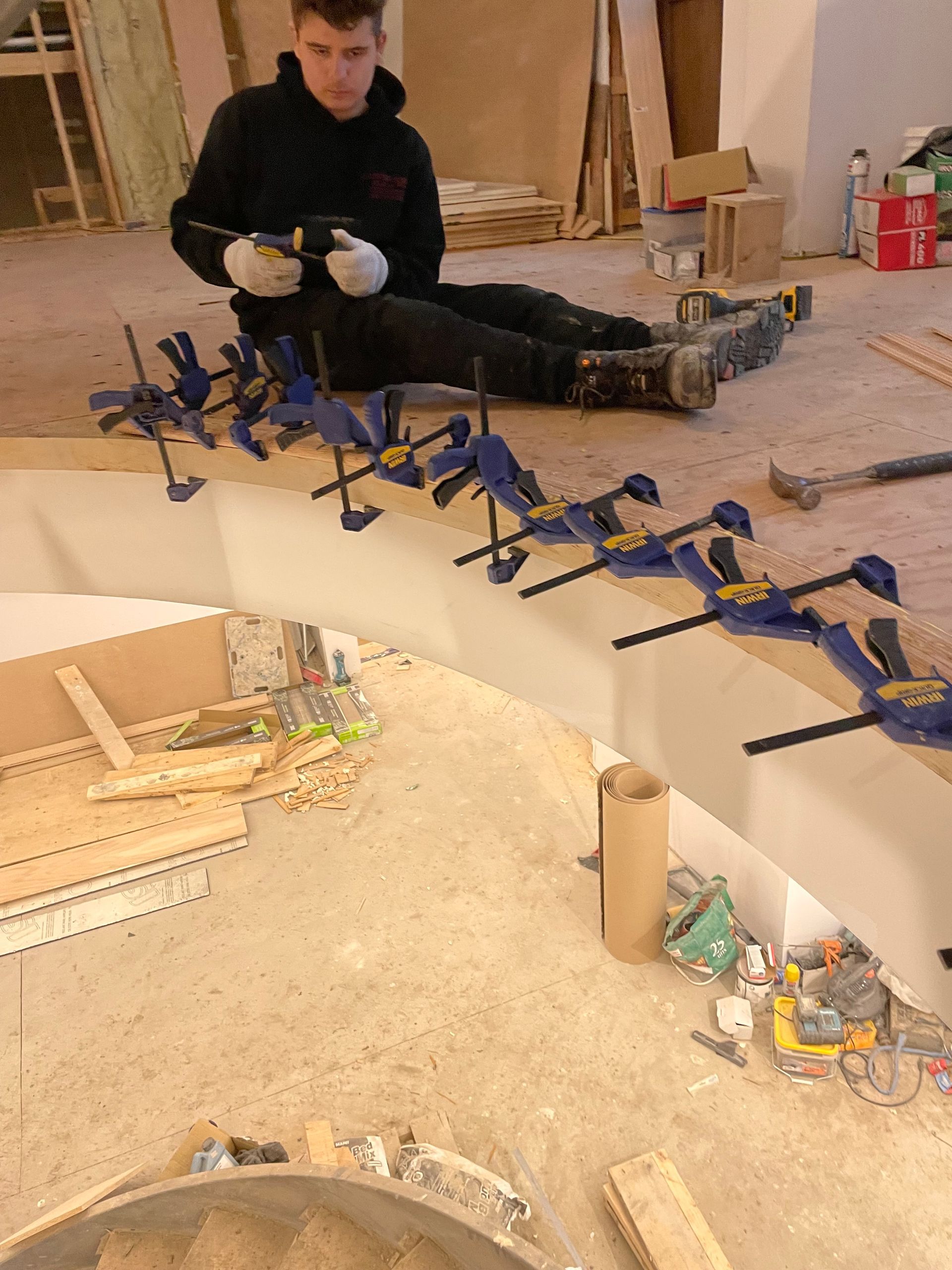 Un homme est assis par terre à l'aide de pinces sur un morceau de bois.