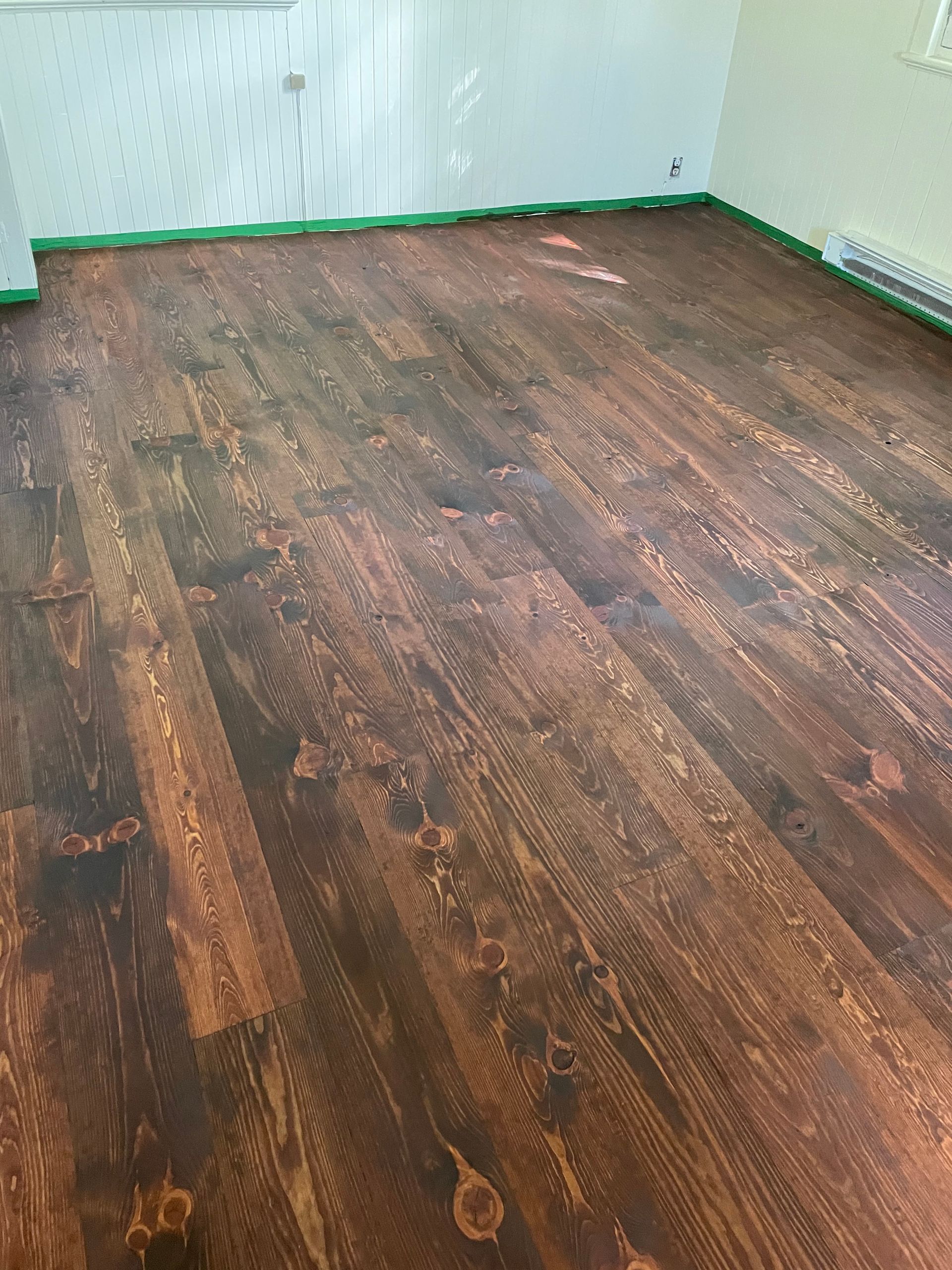 Une pièce avec un plancher en bois et un mur blanc.