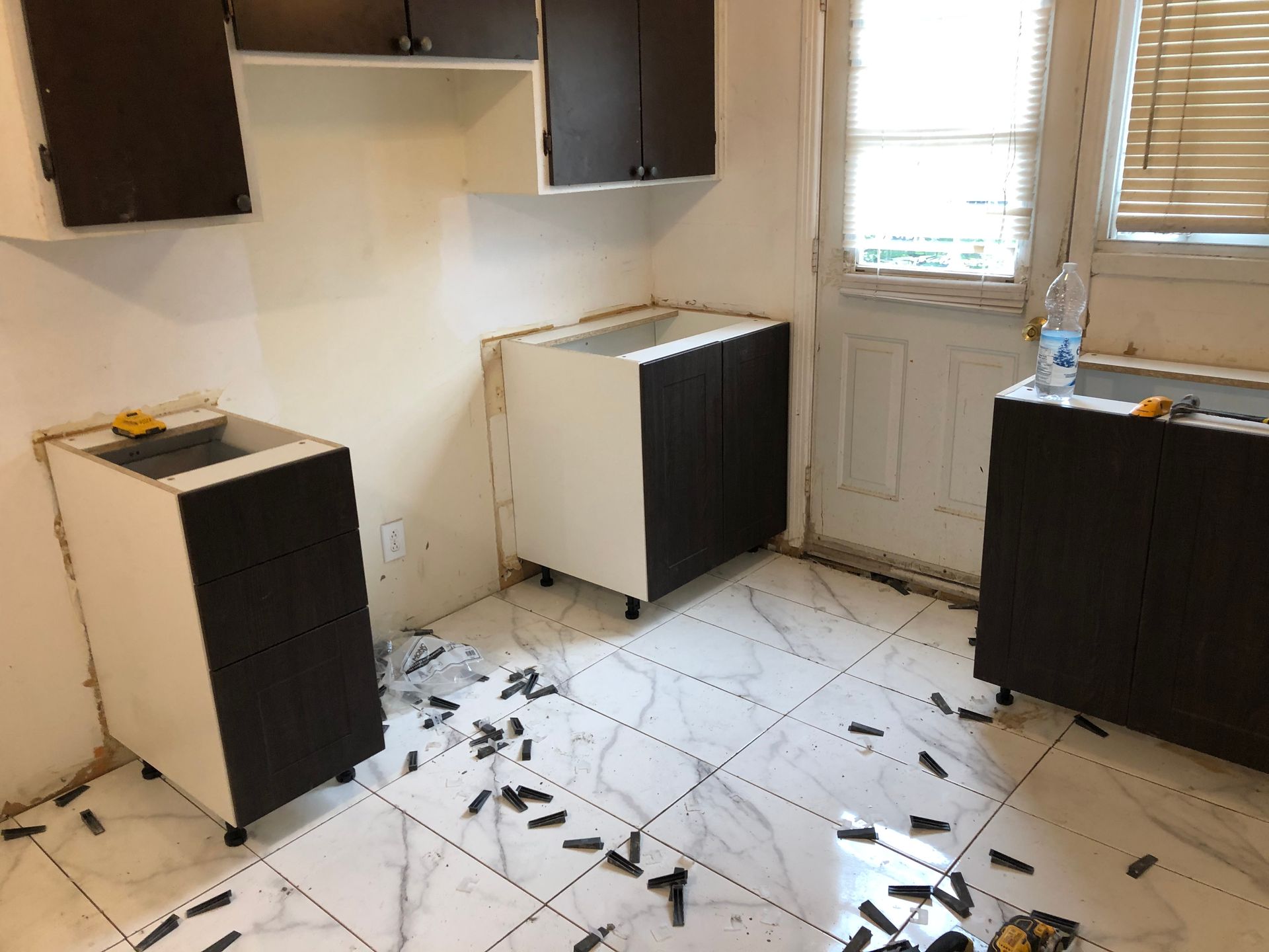 Une cuisine est en cours de rénovation avec des armoires noires et des armoires blanches.