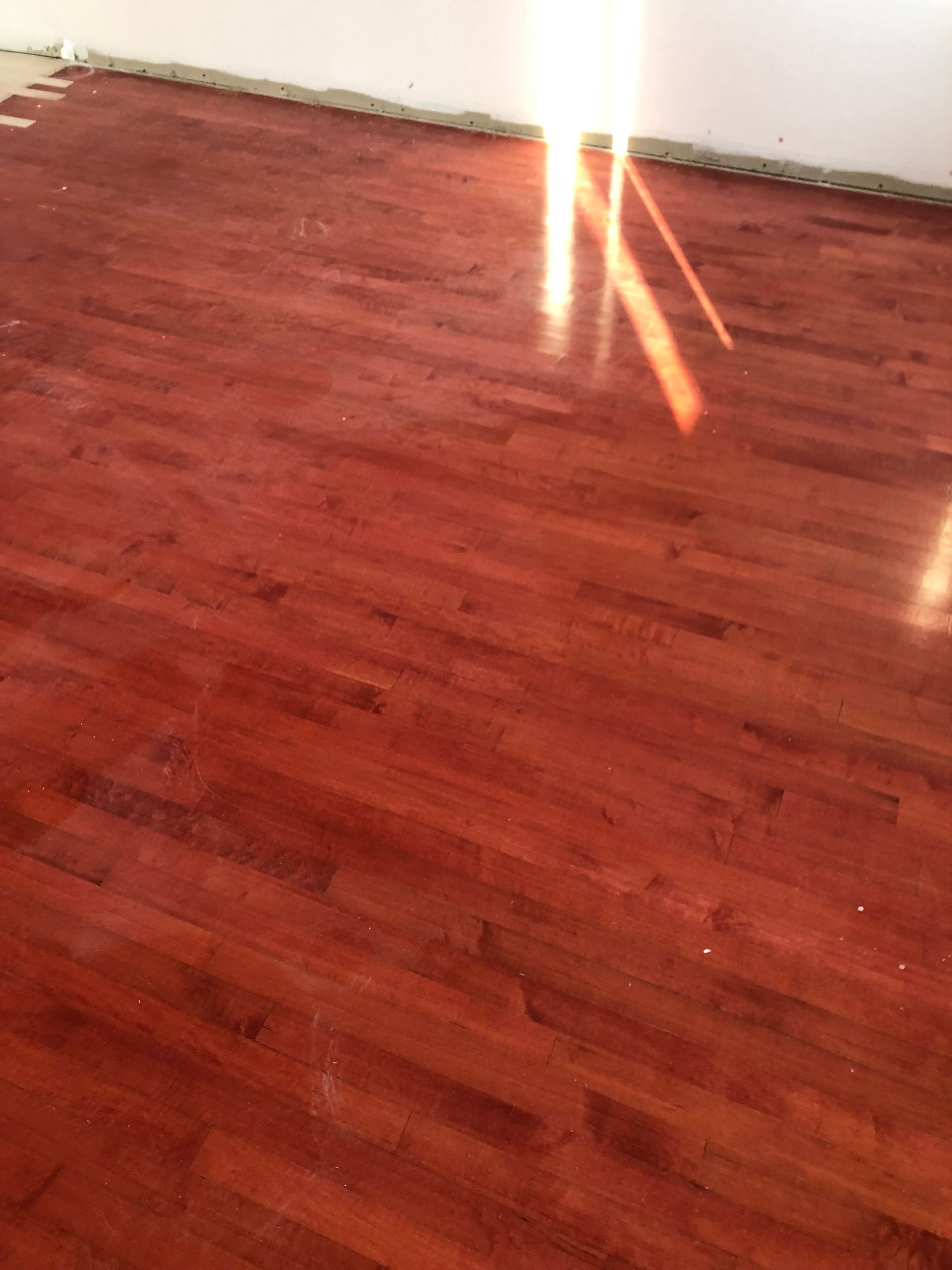 Une pièce avec du parquet et un mur blanc.