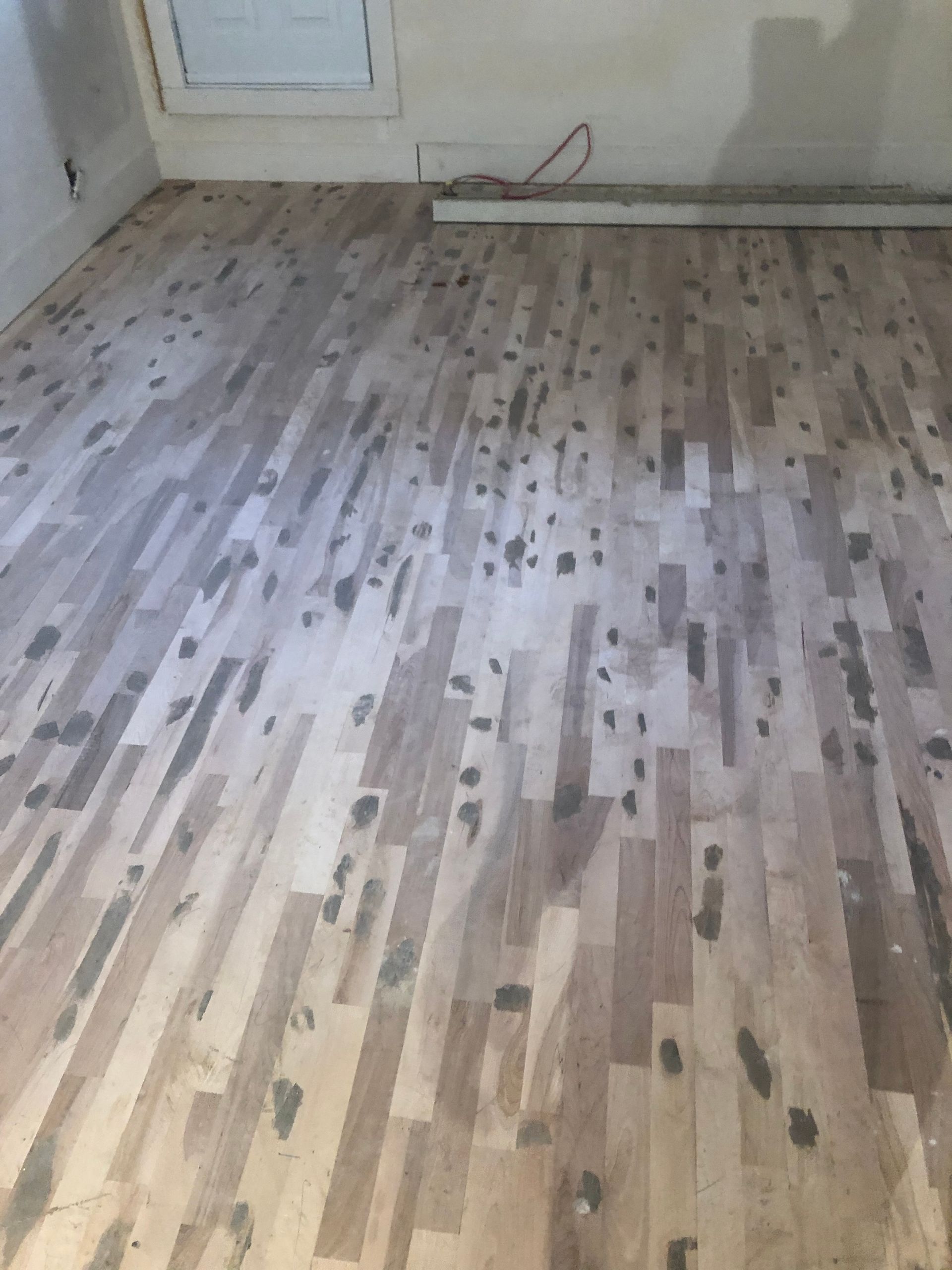 Une pièce avec du parquet et un mur blanc.