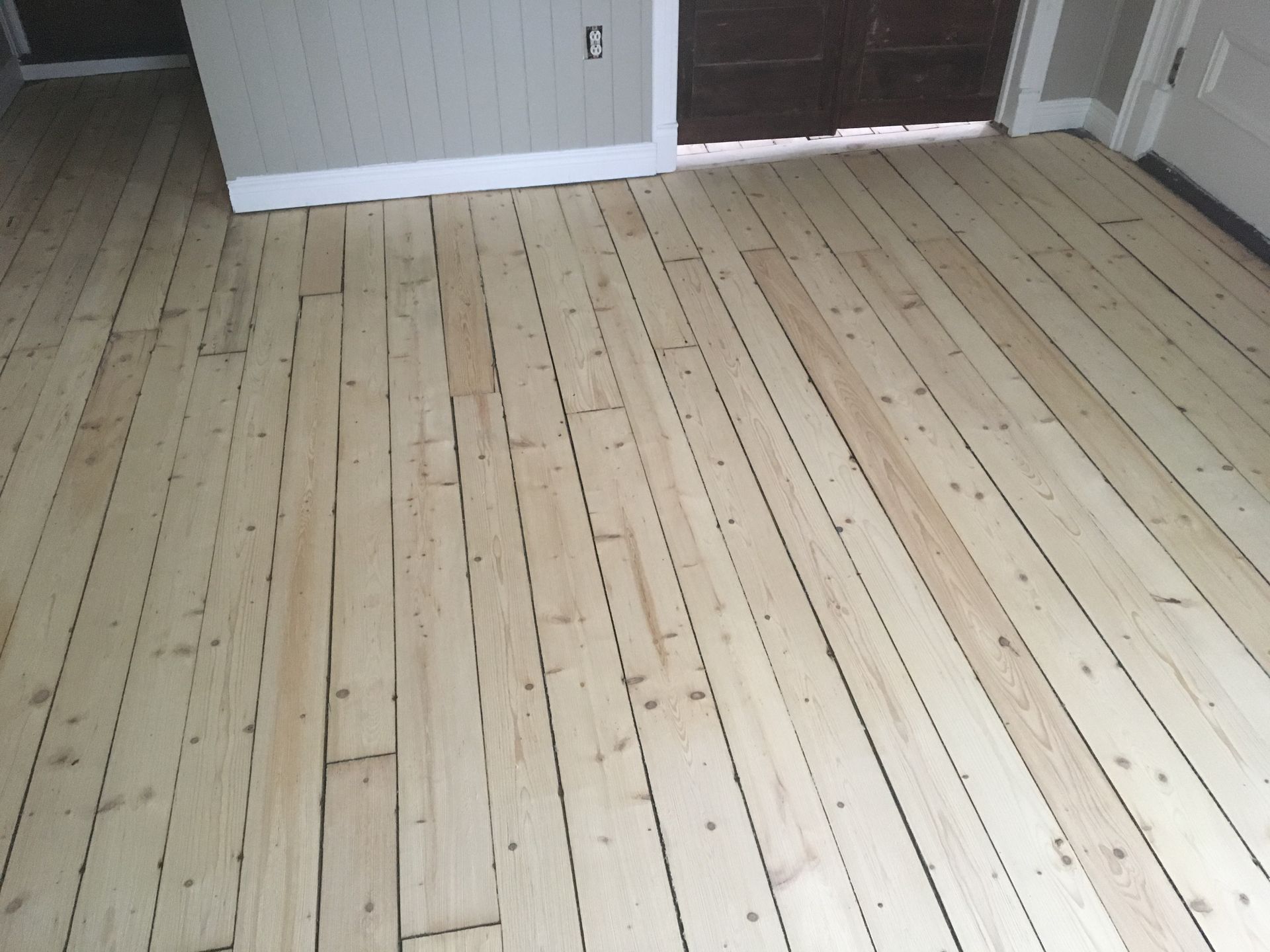 Un séchoir à roulettes supporte de nombreuses planches de bois clair dans un atelier.