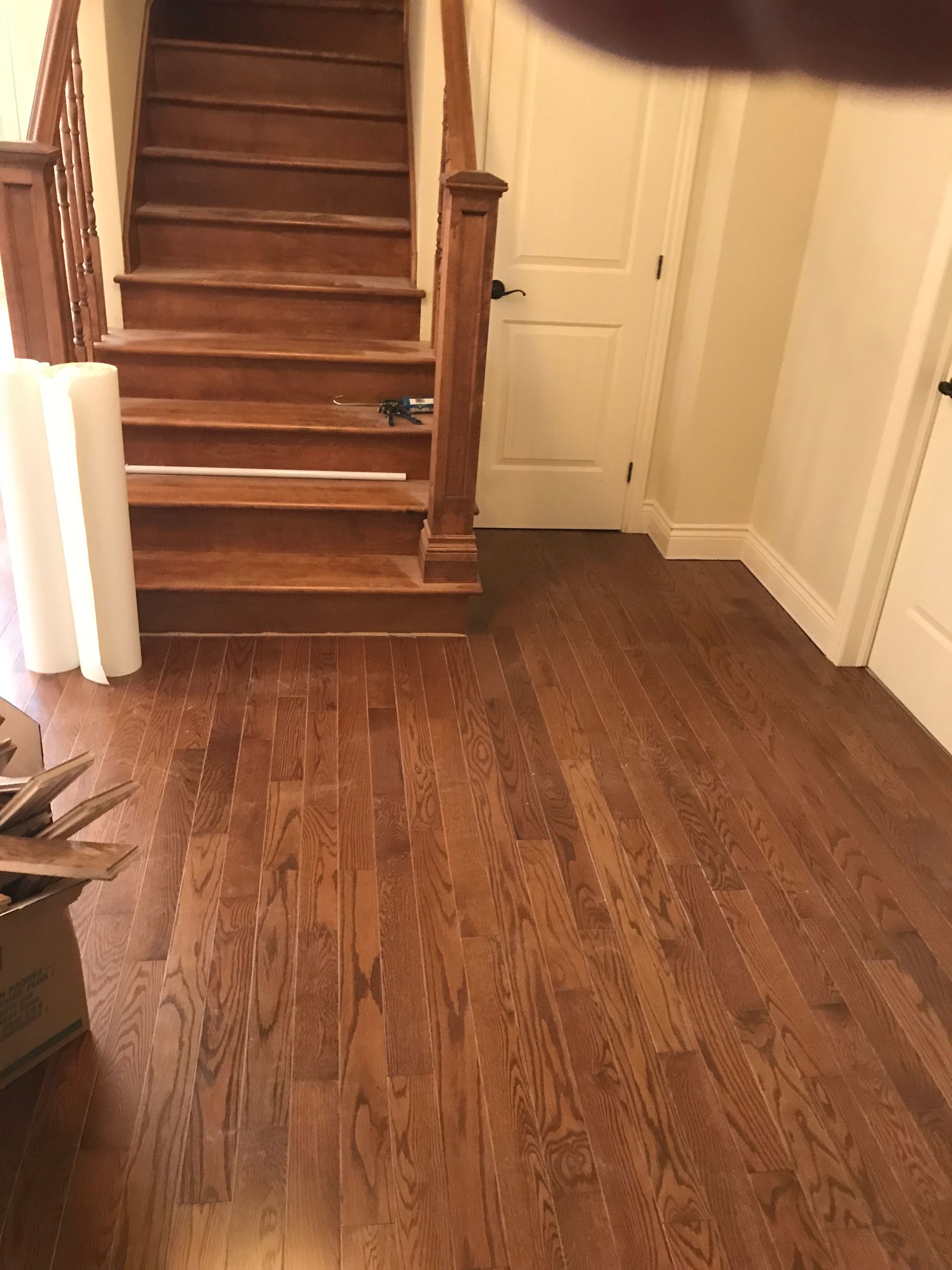 Un couloir avec parquet et escaliers dans une maison.