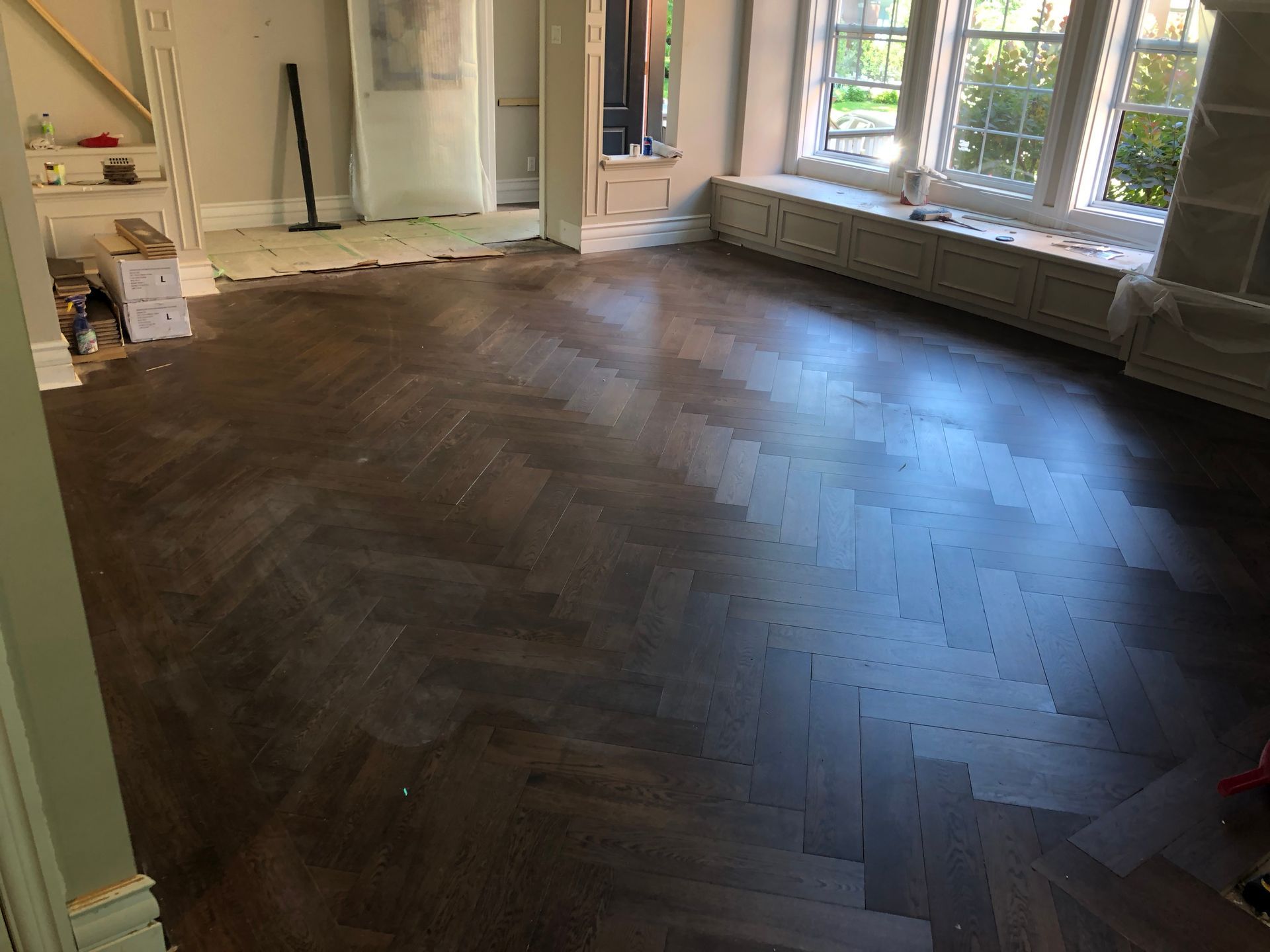 Un salon avec un plancher en bois et une banquette près de la fenêtre.