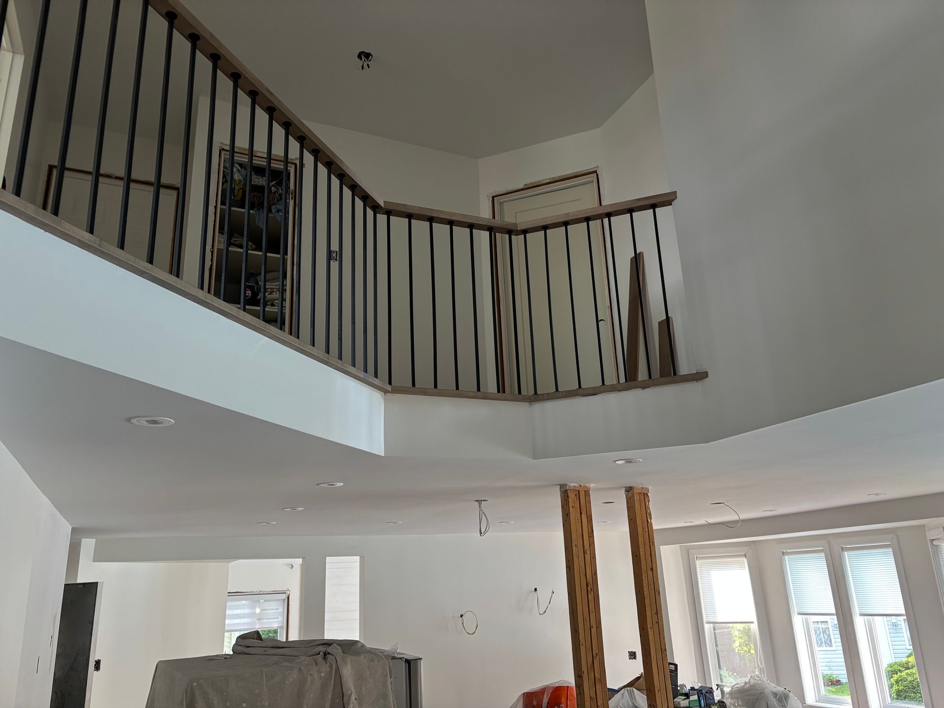 Vue intérieure : Un espace à deux étages avec un balcon, une balustrade en fer noir et des murs blancs.