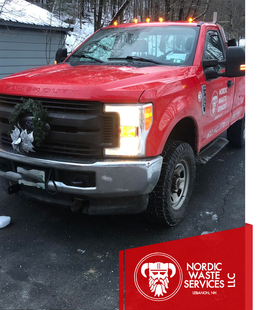 Red Nordic Waste Services truck with a wreath on the front, parked on a snowy driveway.