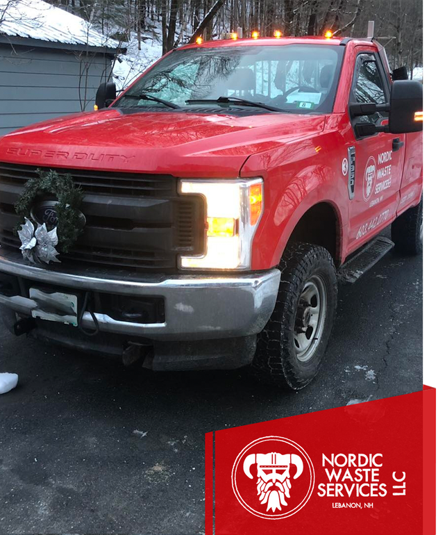 Red Nordic Waste Services truck with a wreath on the front, parked on a snowy driveway.