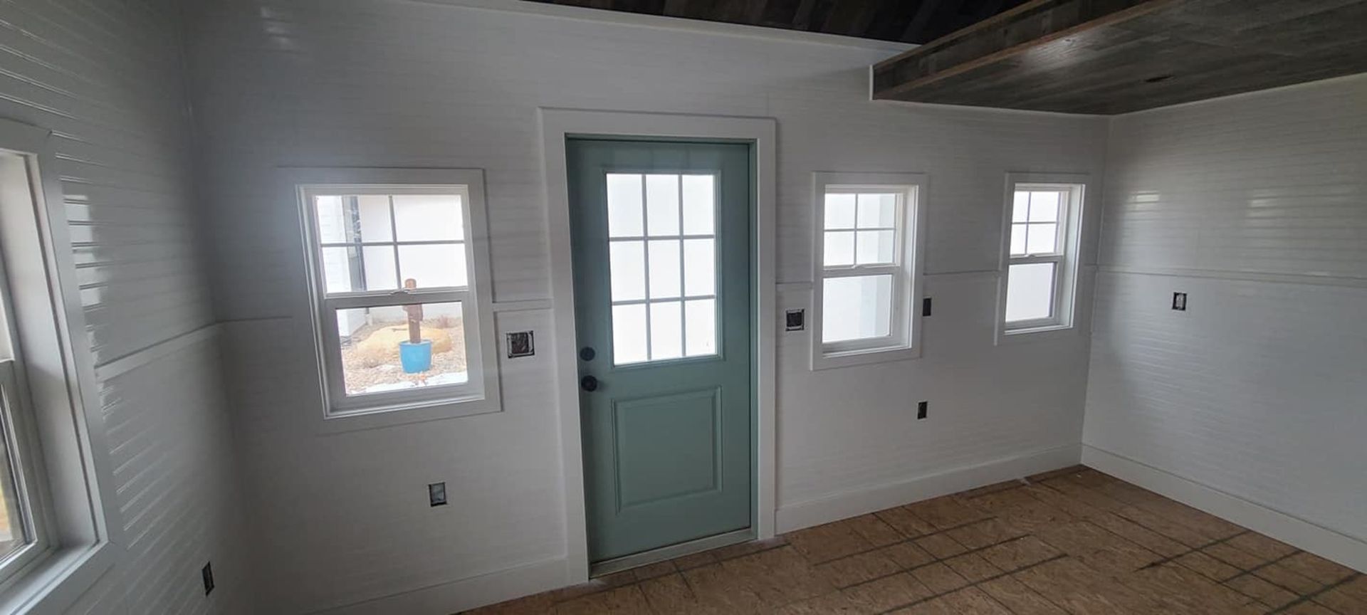An empty room with a blue door and windows.
