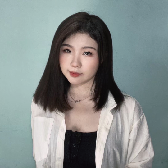 一位身穿白襯衫和黑色上衣的女子站在一面藍色的牆前。