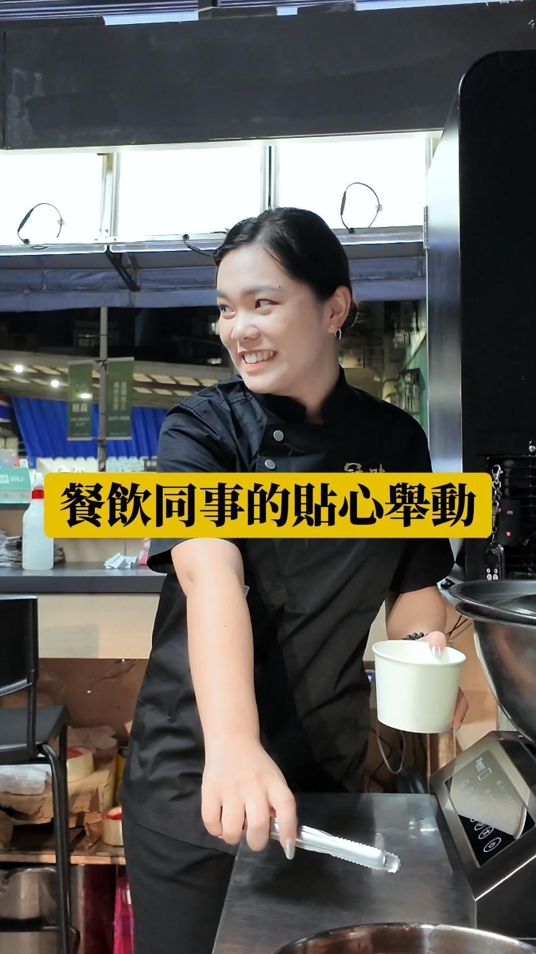 一位身穿廚師制服的女子在廚房做飯時面帶微笑。