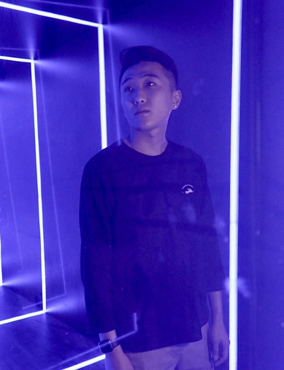 一名身穿黑色襯衫的男子站在一盞藍燈前。