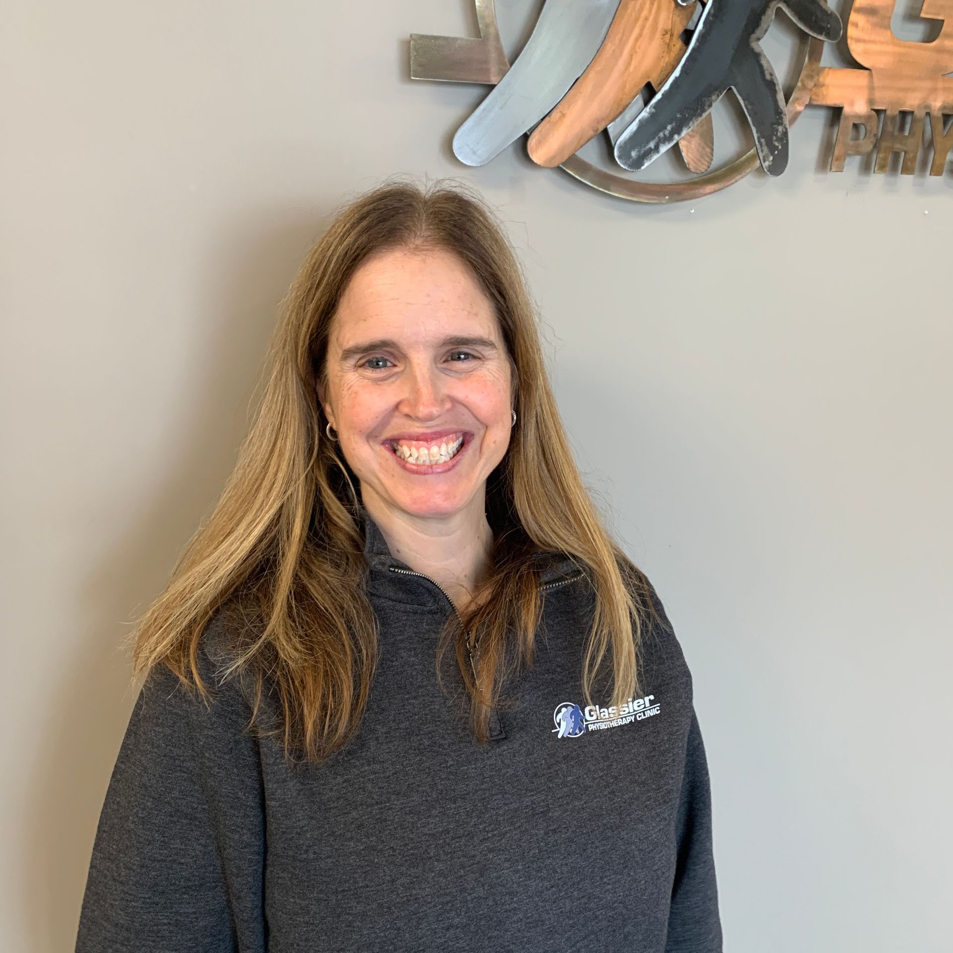 A woman is smiling in front of a wall 