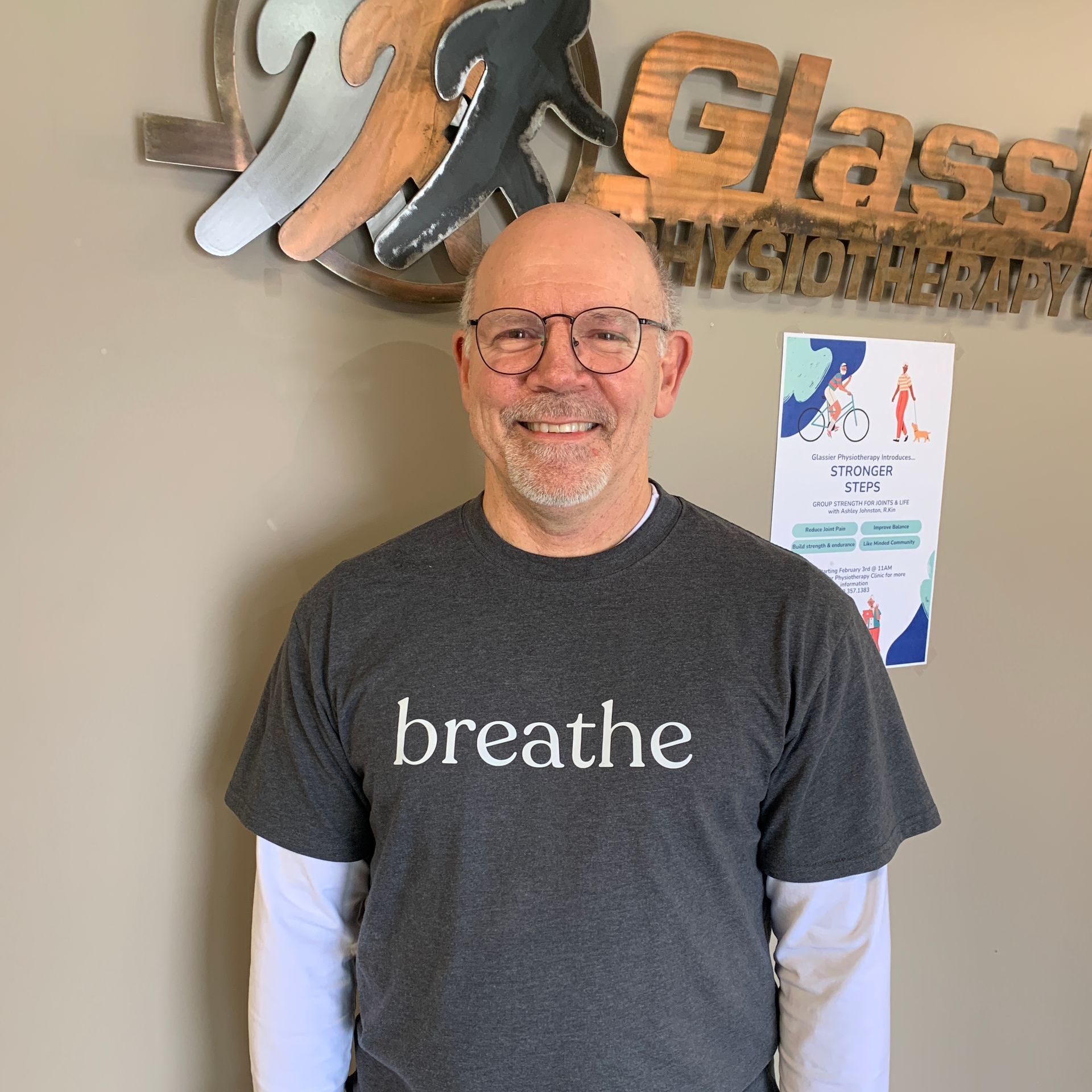 A man wearing glasses and a t-shirt that says breathe