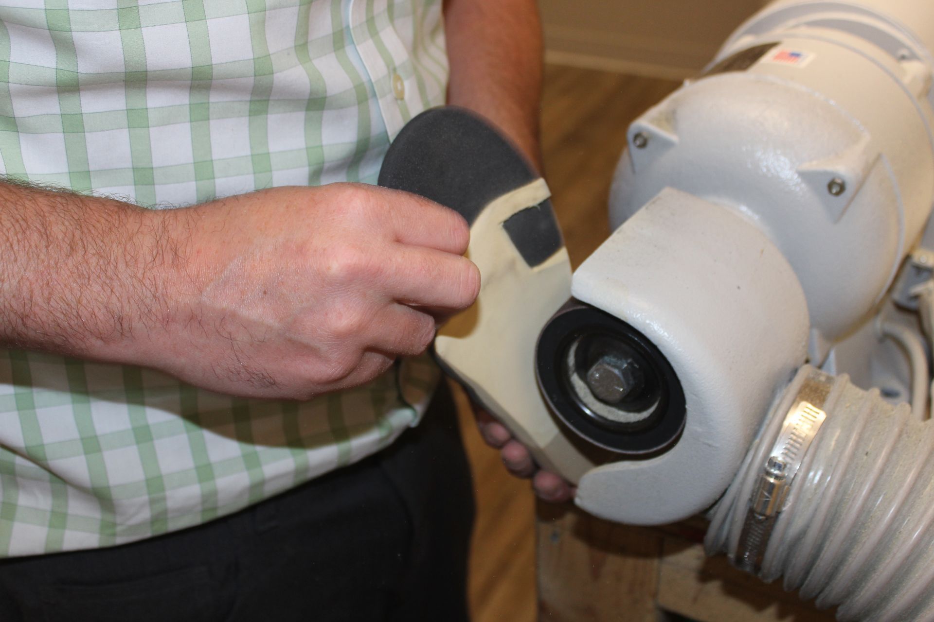 A man is sanding a piece of wood with a sanding sponge.