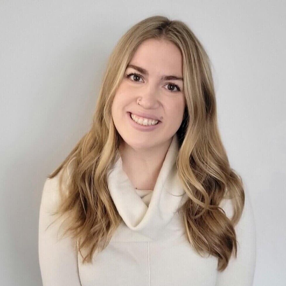The woman is wearing a white sweater and smiling for the camera.
