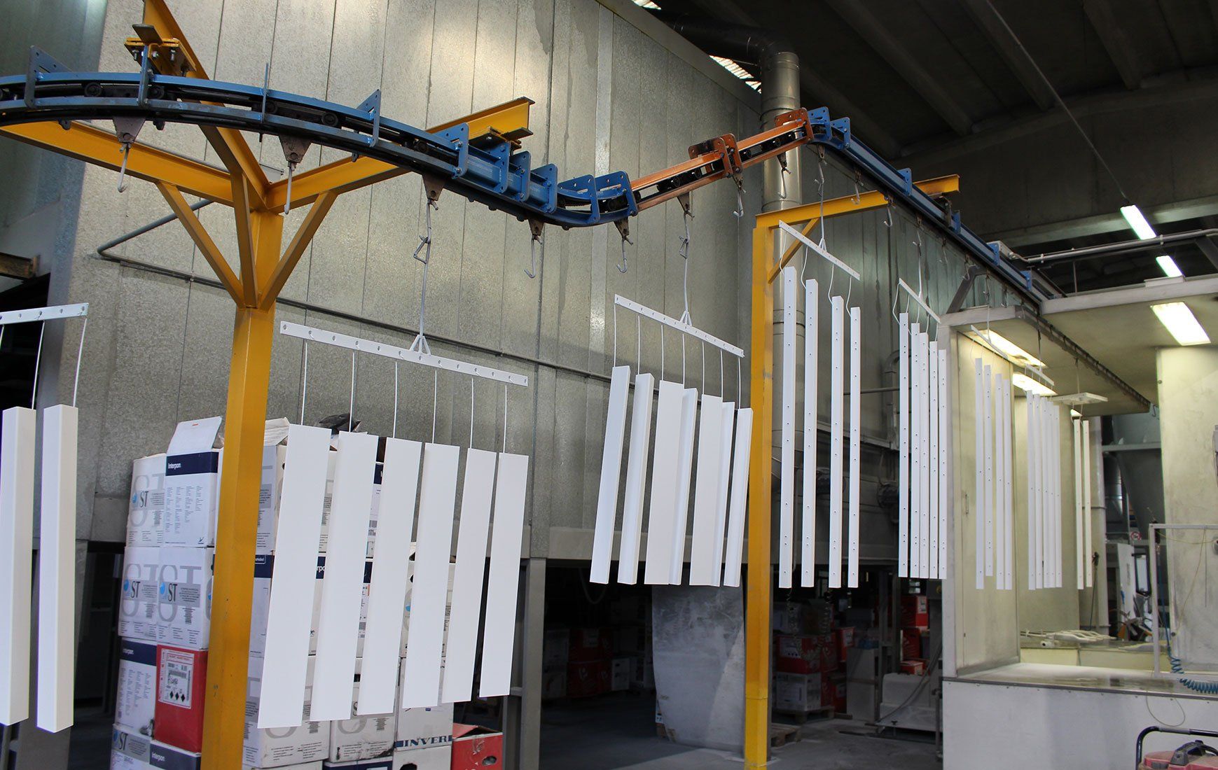 Una fabbrica con un nastro trasportatore che trasporta pezzi bianchi di metallo