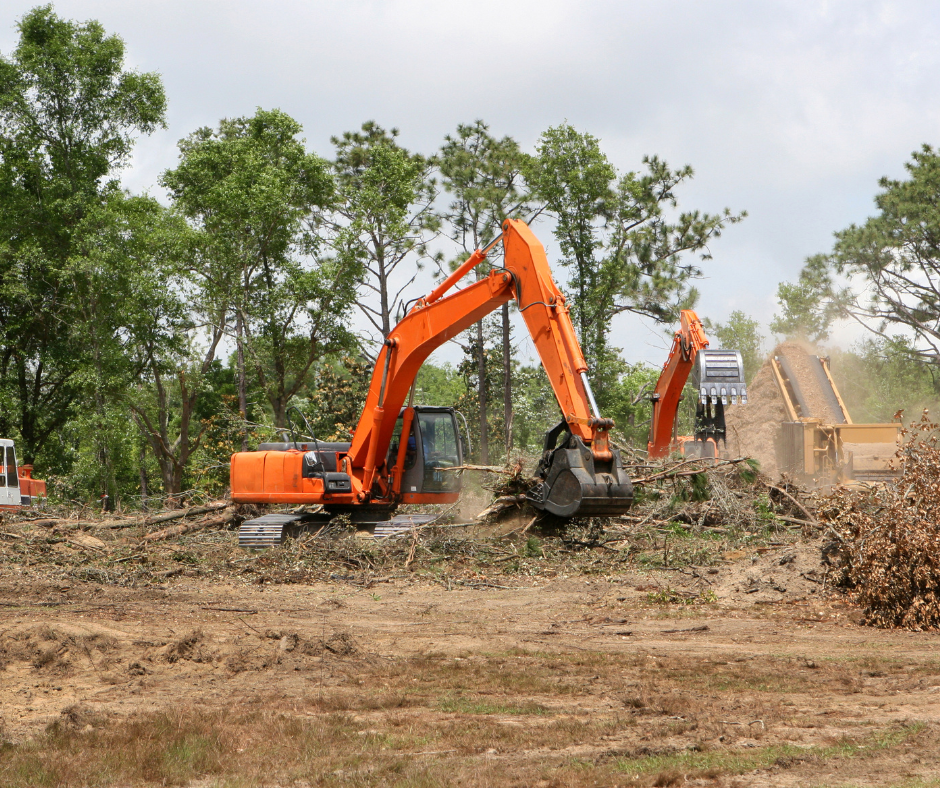 A large orange excavator is moving dirt in a field.