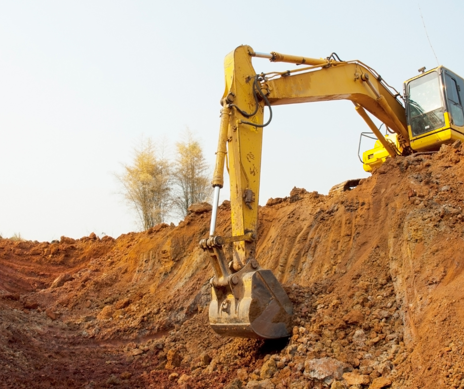 A yellow excavator is digging a hole in the dirt