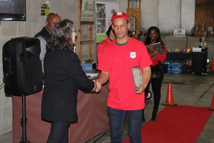 A man in a red shirt is shaking hands with a woman