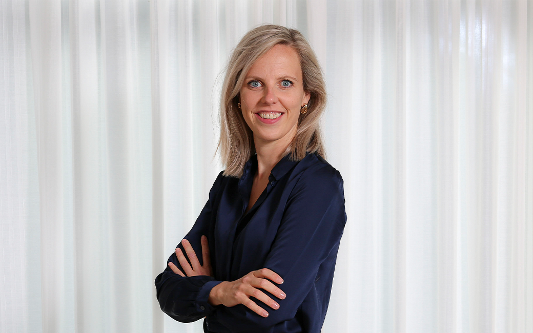 Vrouw die met gekruiste armen glimlachend in de camera kijkt