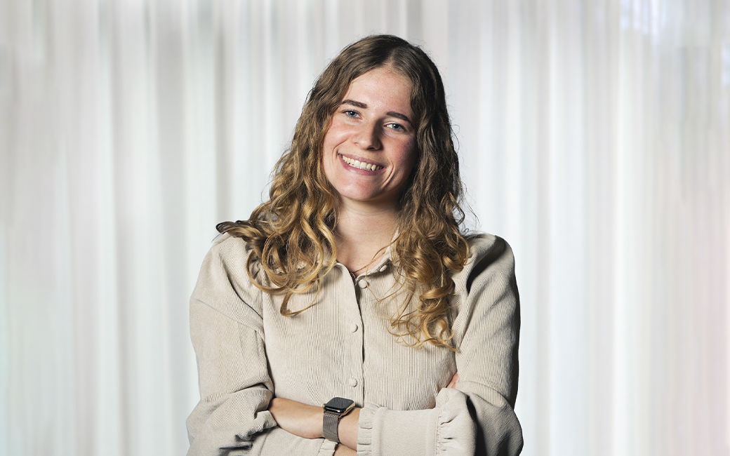 Vrouw met krullend haar die met gekruiste armen lacht naar de camera