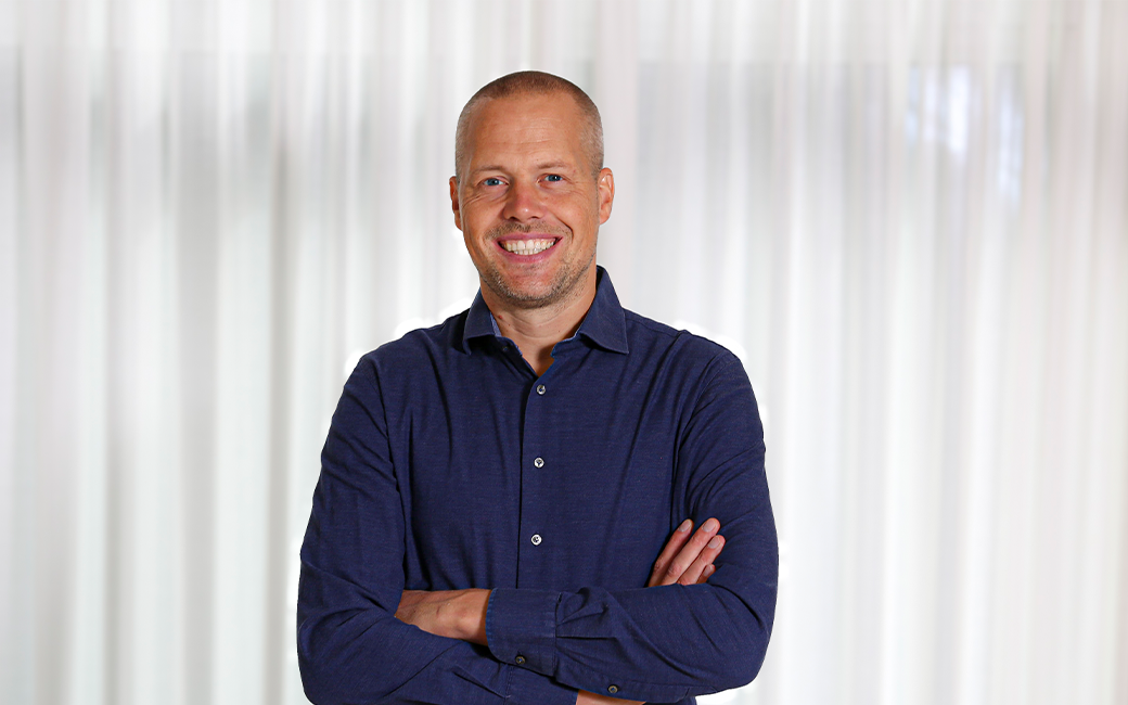 Man die met gekruiste armen lachend in de camera kijkt