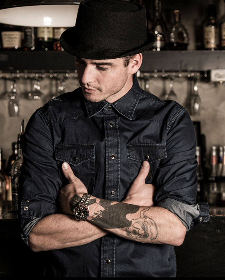 Barman met hoed die achter de bar staat