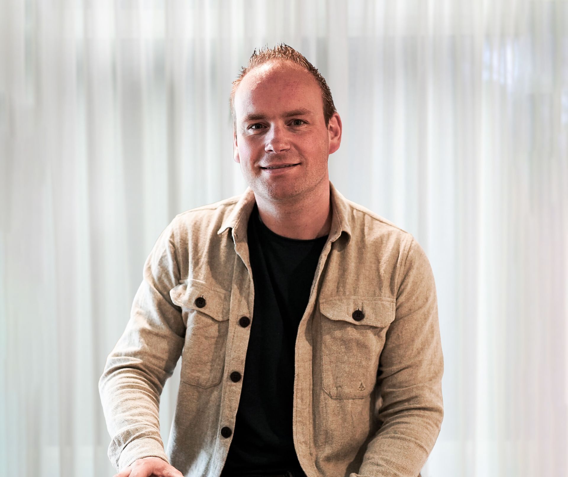 Vrouw die met gekruiste armen lachend in de camera kijkt