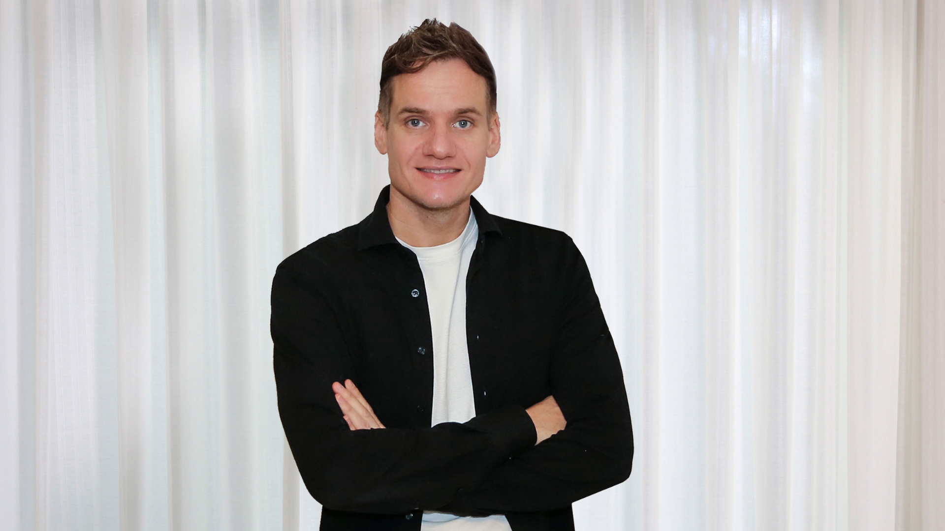 Vrouw die met gekruiste armen lachend in de camera kijkt