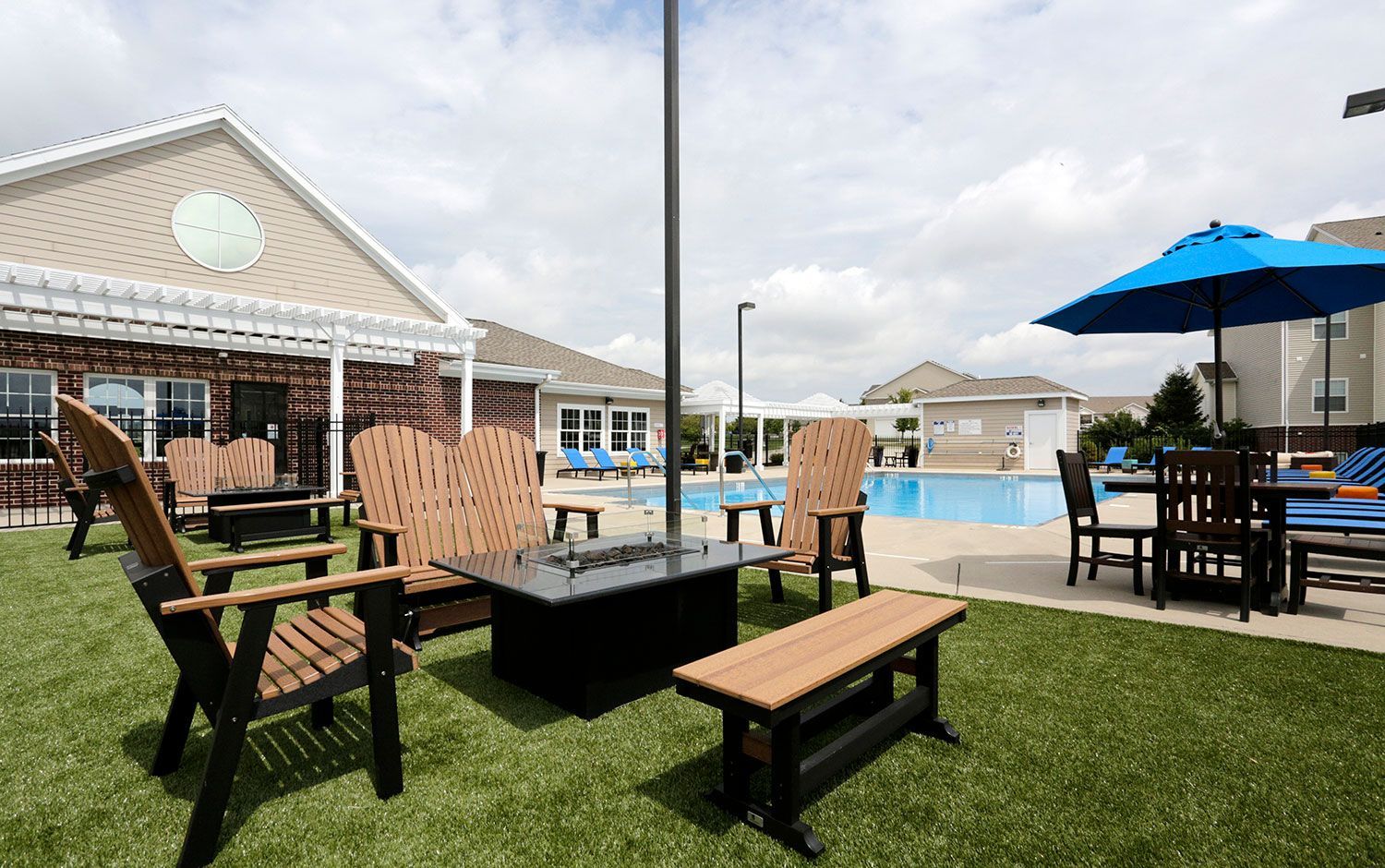 a lawn with chairs and umbrellas in front of a swimming pool