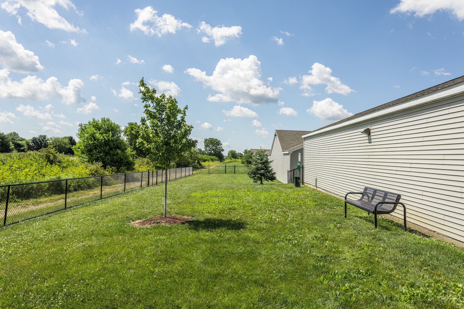 a bench sits in the grass in front of a house