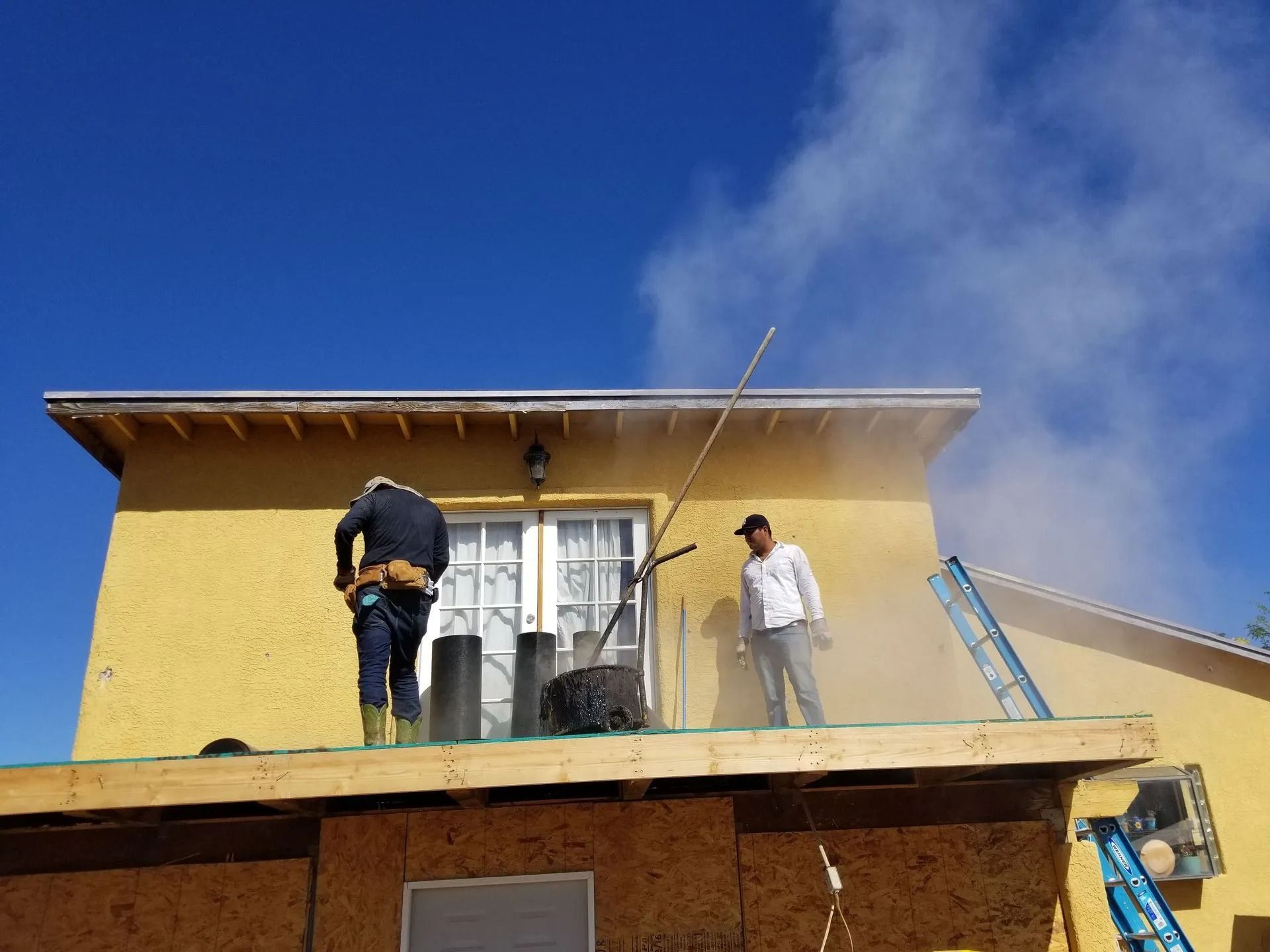 Two men are working on the roof of a house.