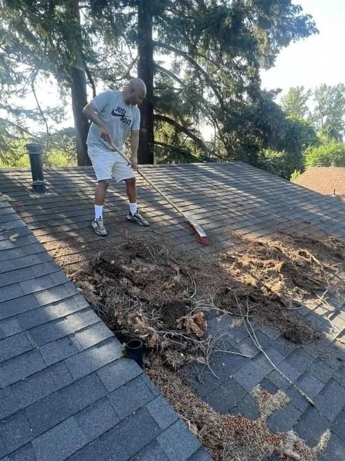 A man is sweeping the roof of a house with a broom.