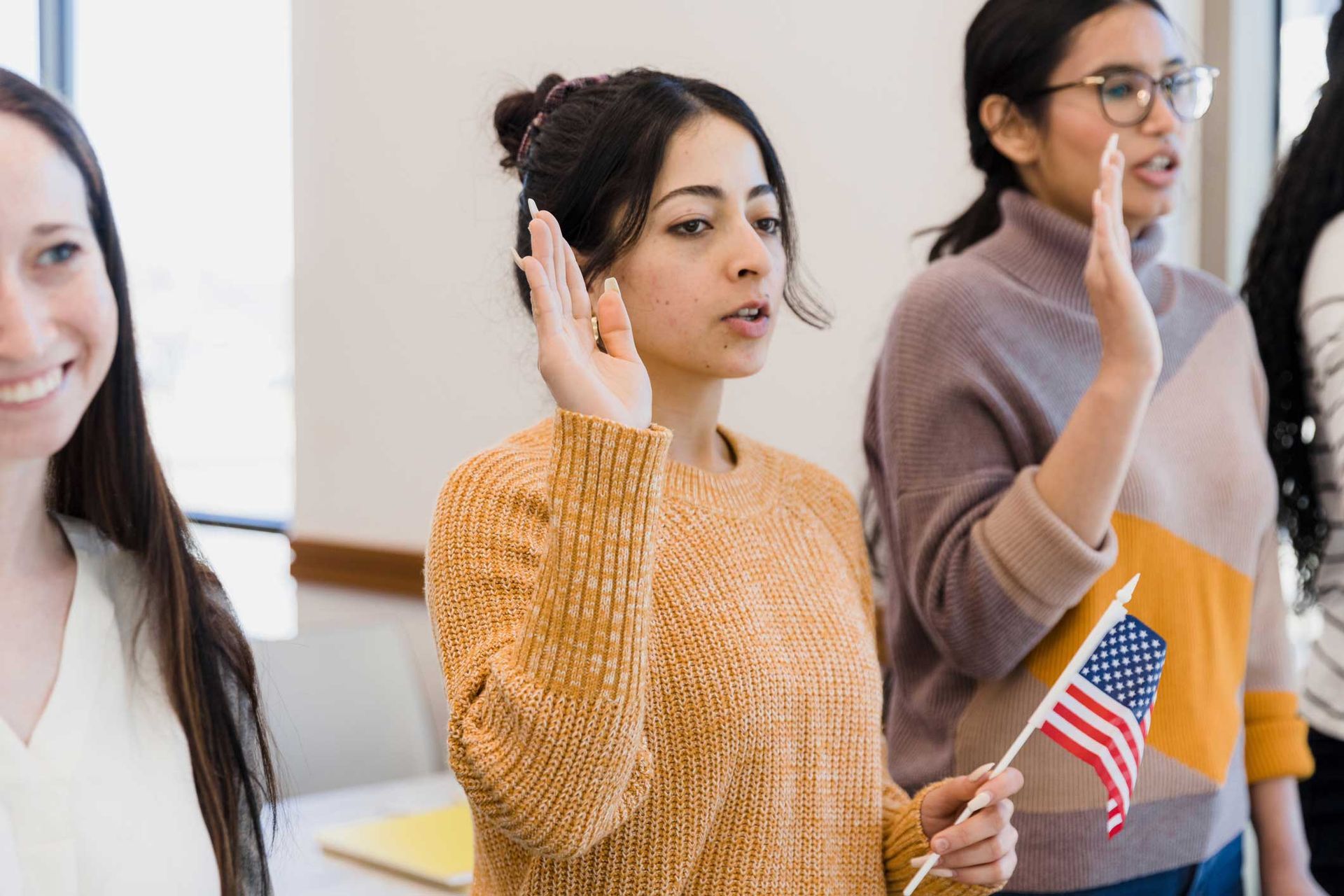 A group of women are standing next to each other and one of them is holding an american flag.