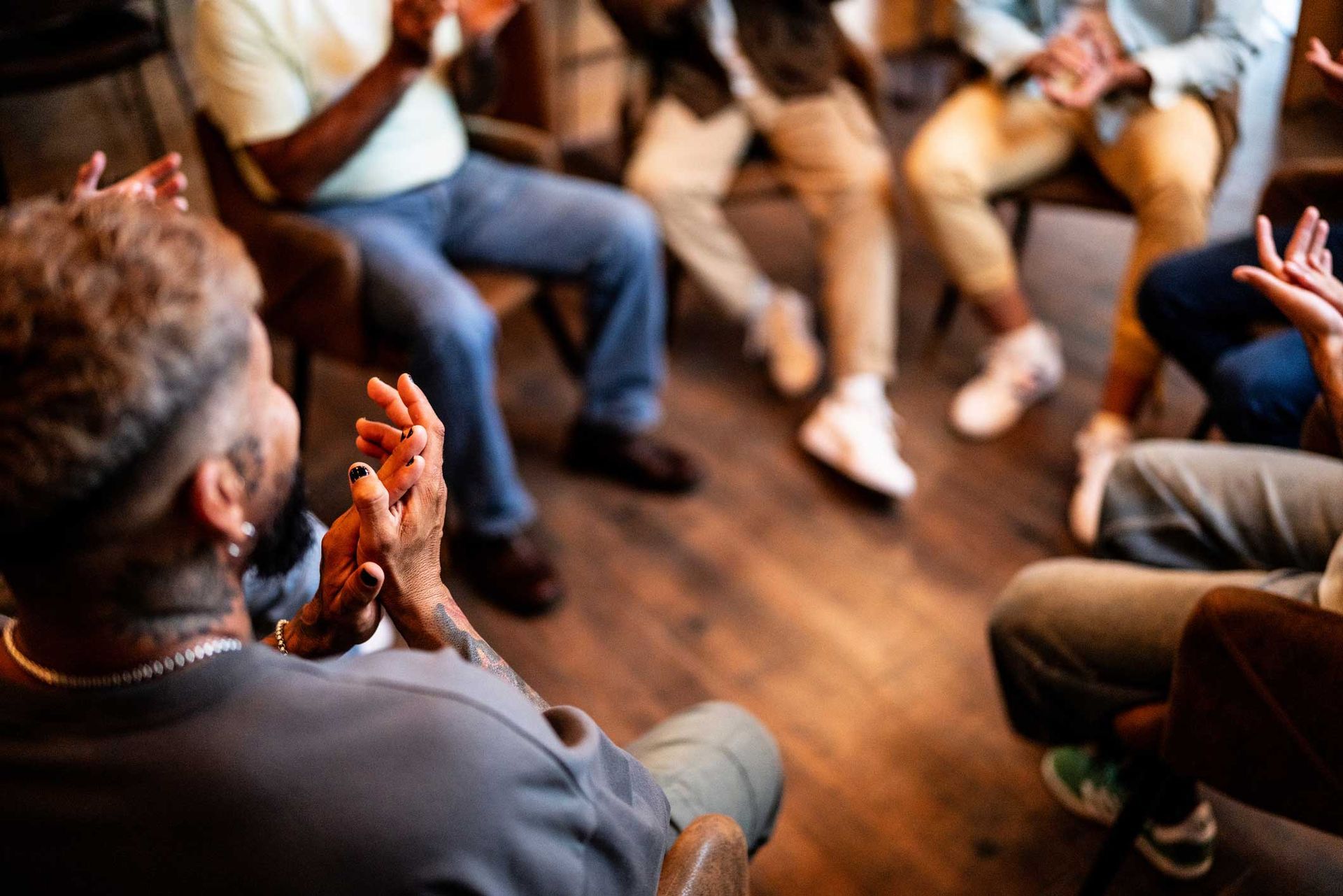 A group of people are sitting in a circle clapping their hands.