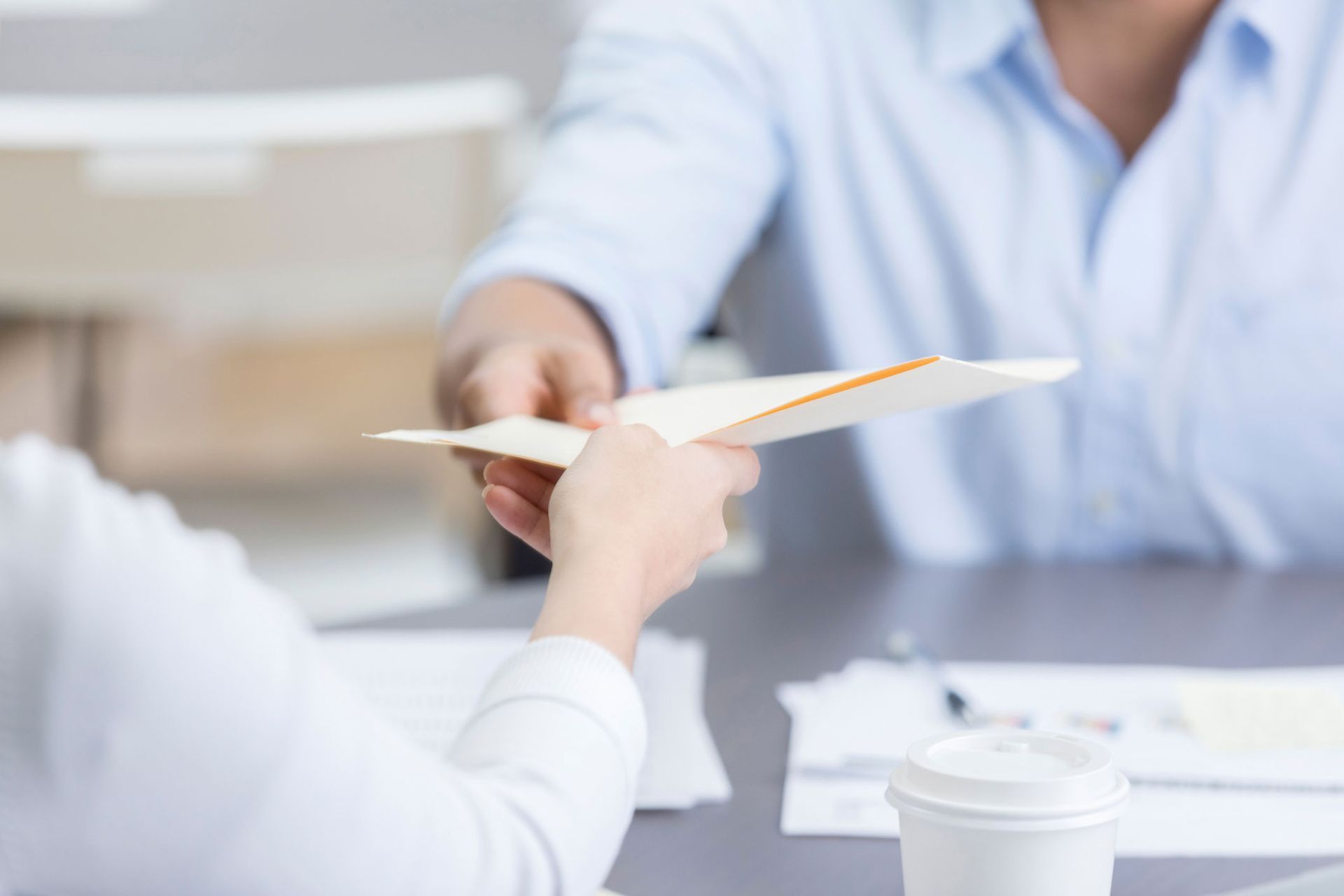 A man is handing an envelope to a woman at a table.