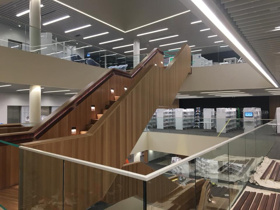 A wooden staircase in a building with a glass railing