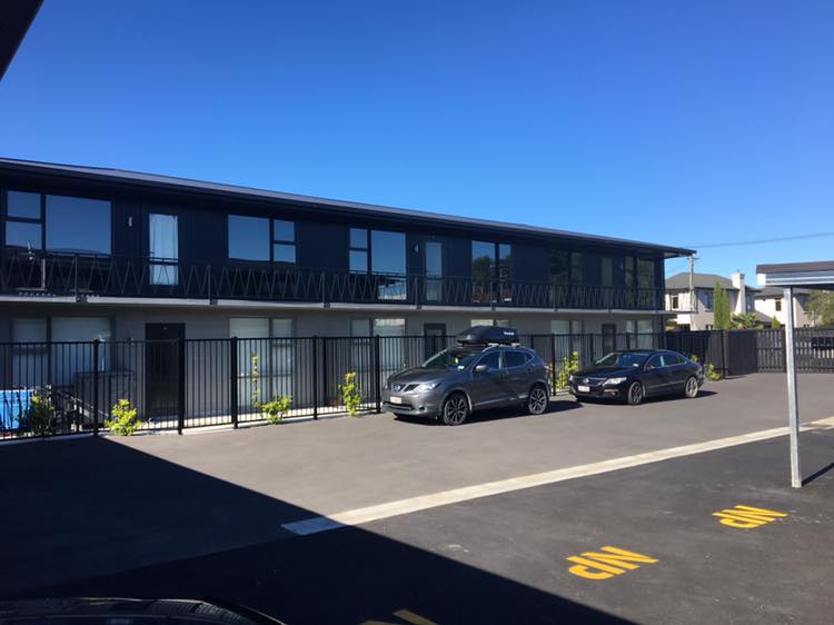 A row of cars are parked in front of a building.