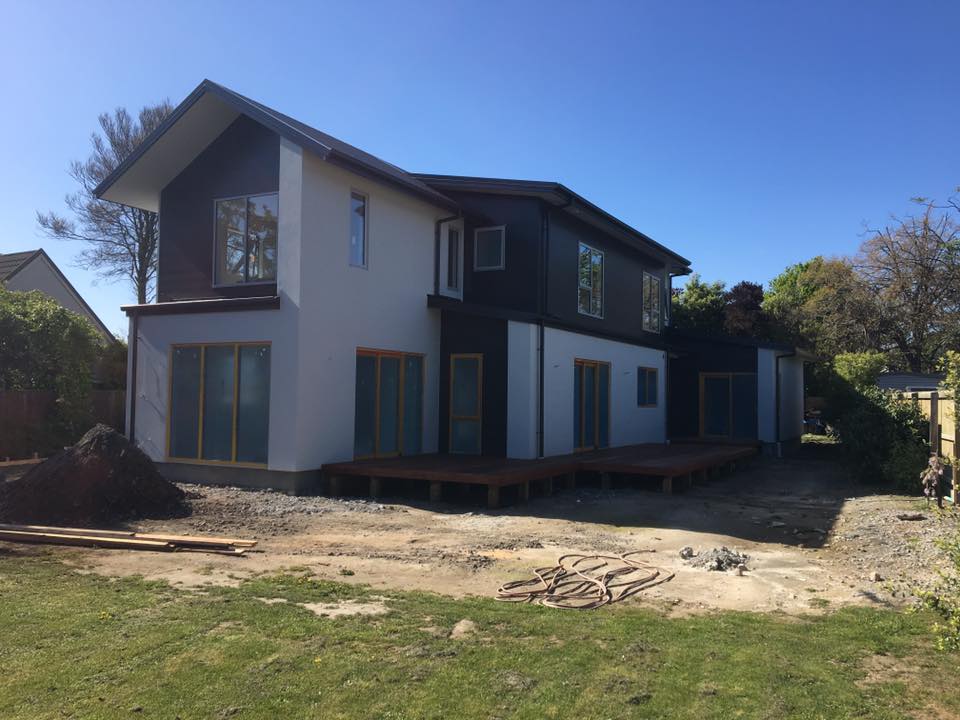 A large house with a lot of windows is sitting on top of a lush green field.