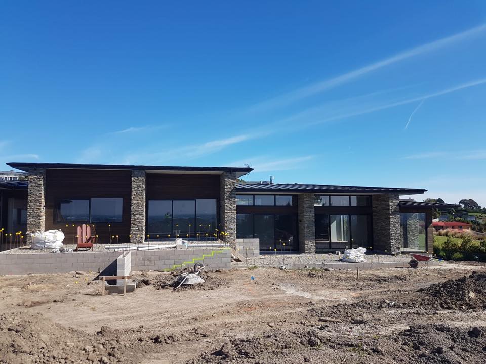 A large house is being built in the middle of a dirt field.