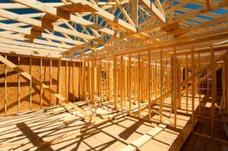 A house is being built with wooden beams and a blue sky in the background.