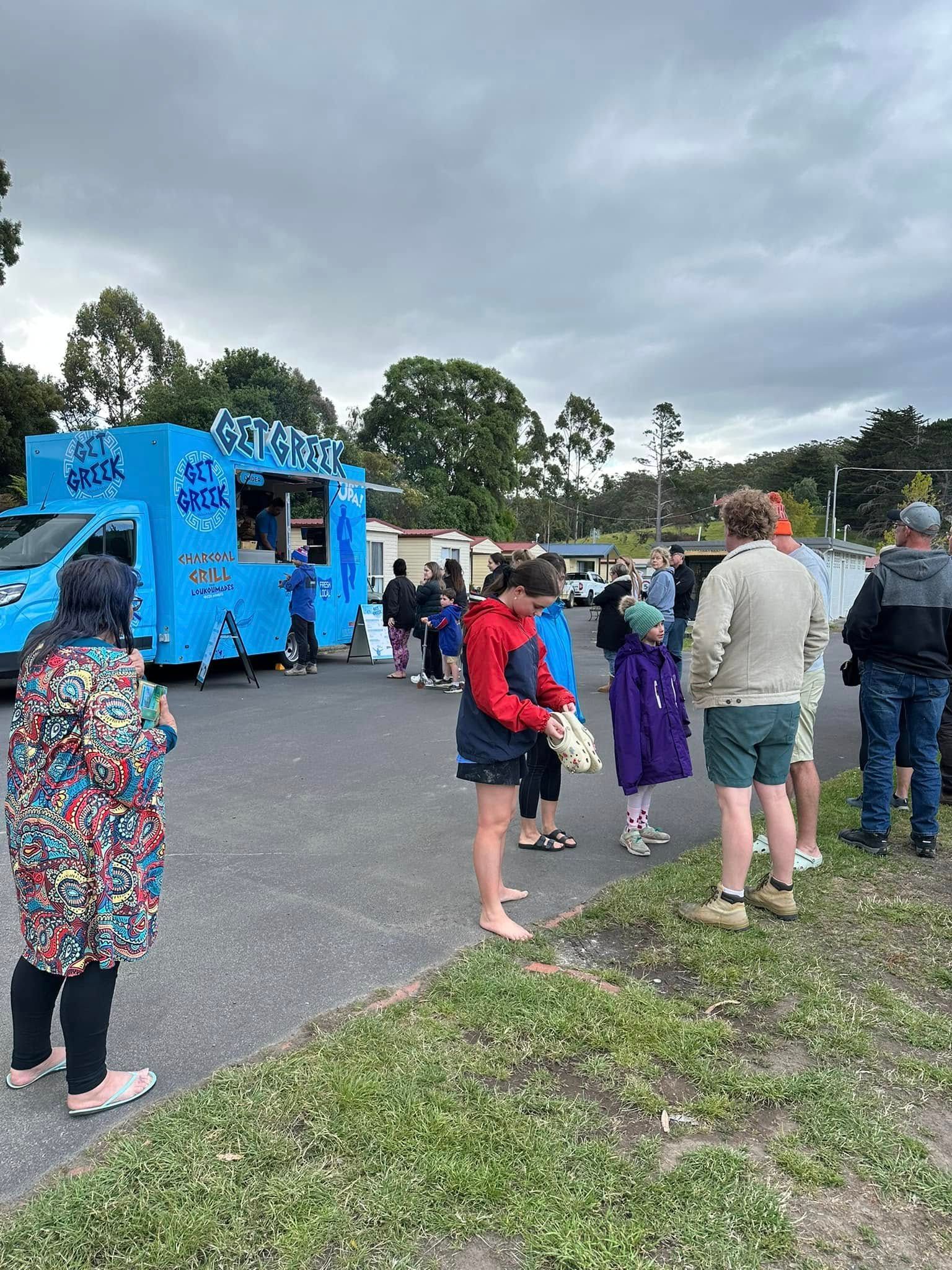 A group of people are standing in front of a food truck.