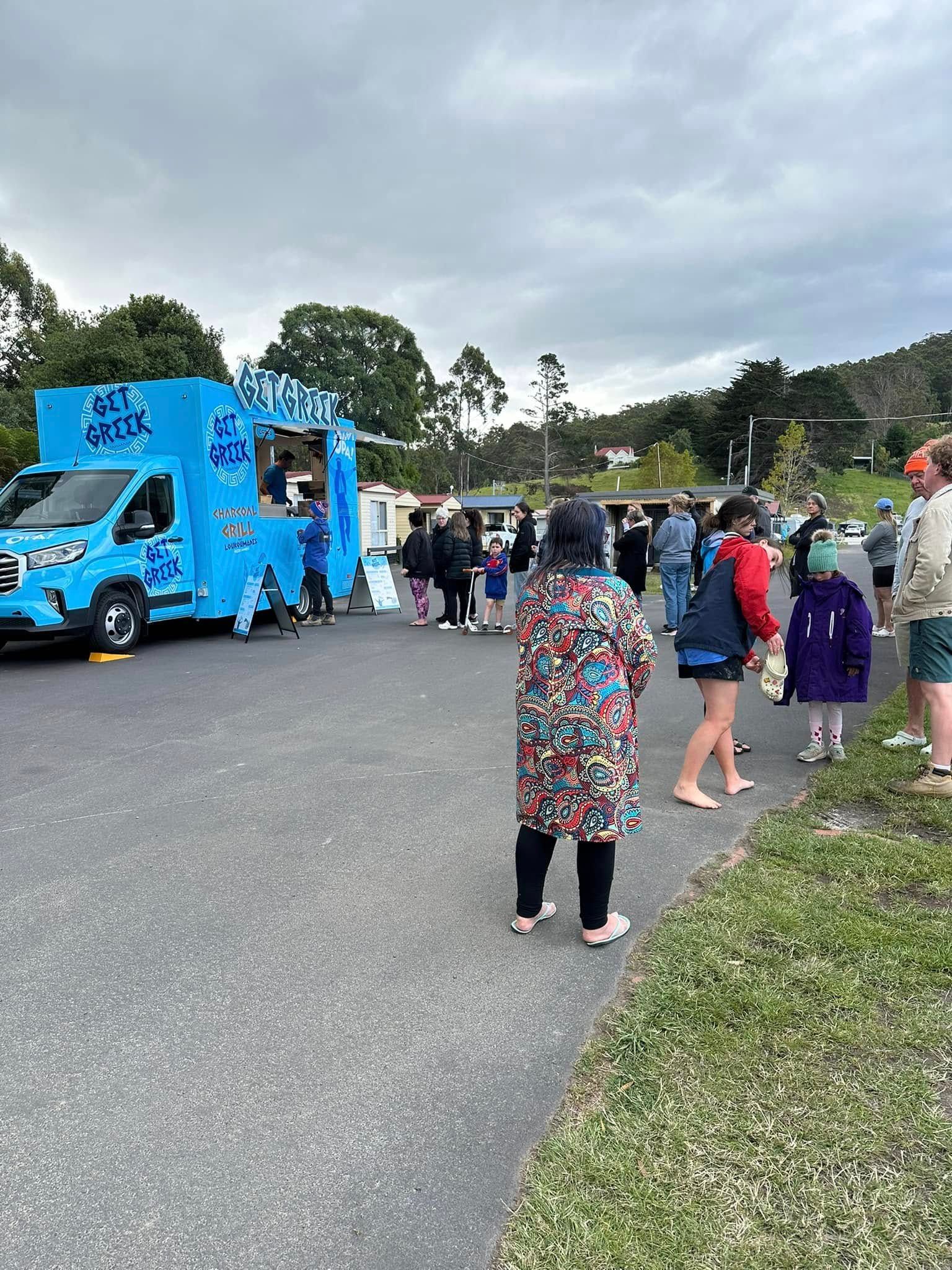 A group of people are standing in front of a blue food truck.