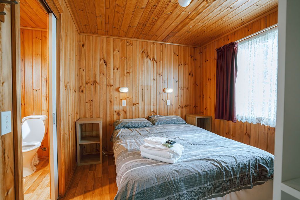 A mature couple sitting together in chairs by a camper trailer in a caravan park cabin rental.